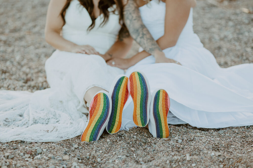 lesbian brides wearing rainbow sneakers on the beach LGBTQ+