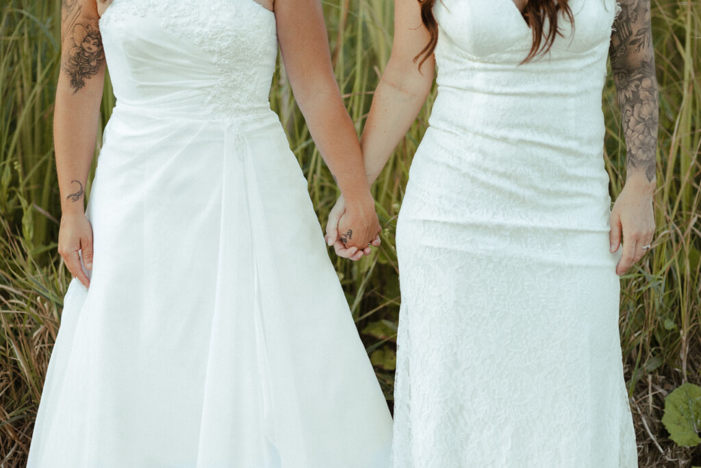 brides in white wedding dresses holding hands