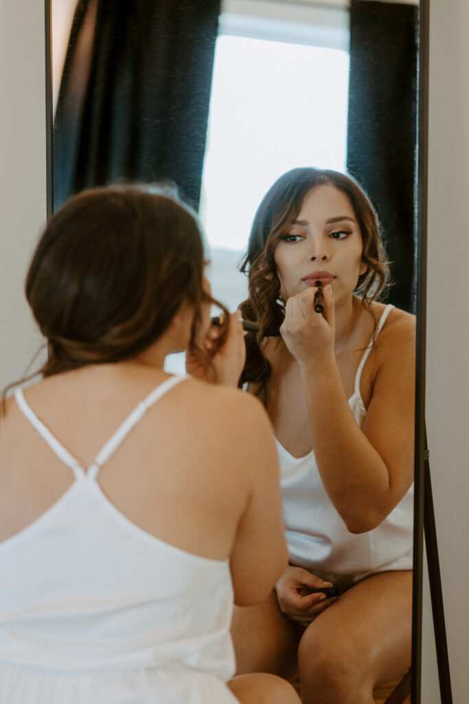 bride applying makeup in the mirror