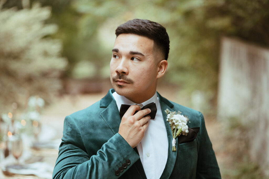 groom with boutonniere adjusting bowtie 