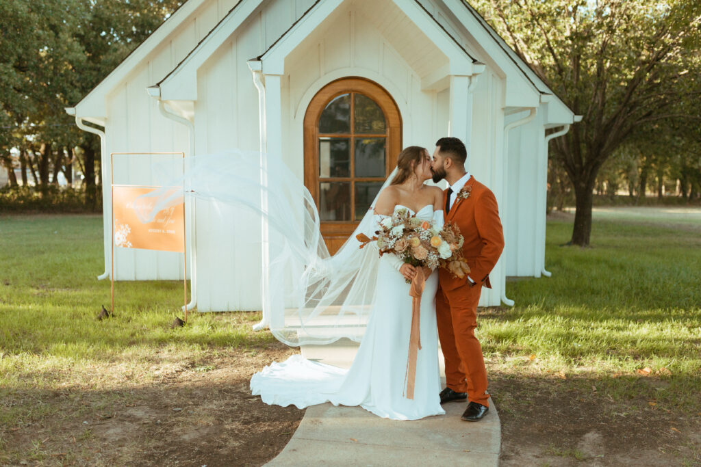 bride and groom kiss infront of the white chapel at the Emerson Venue in East Texas