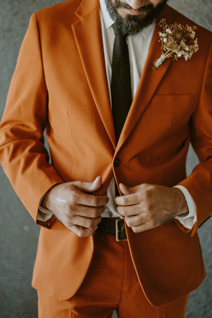 groom in a rust terracotta orange suit