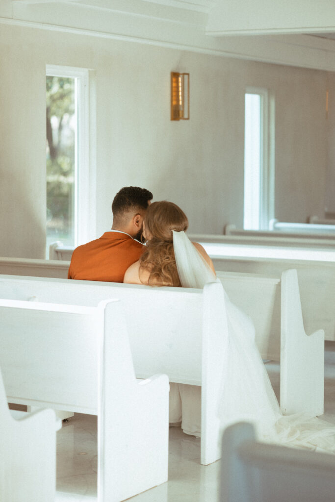 bride and groom sitting in church pews during ceremony
